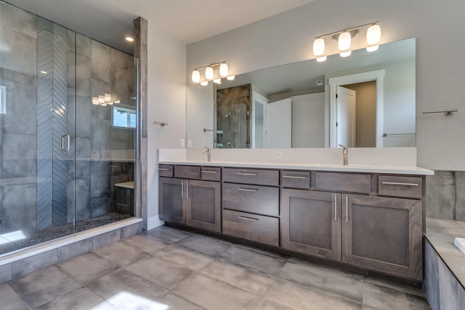 bathroom with large walk-in shower and two sinks in luxurious custom modern home