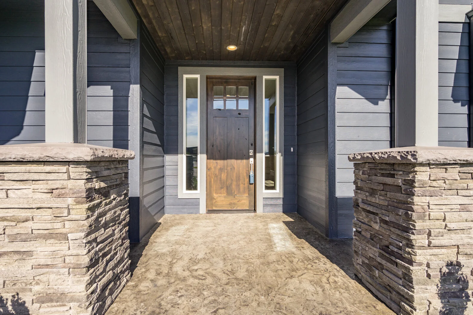 entry patio with intricate stonework leading to luxurious custom modern home